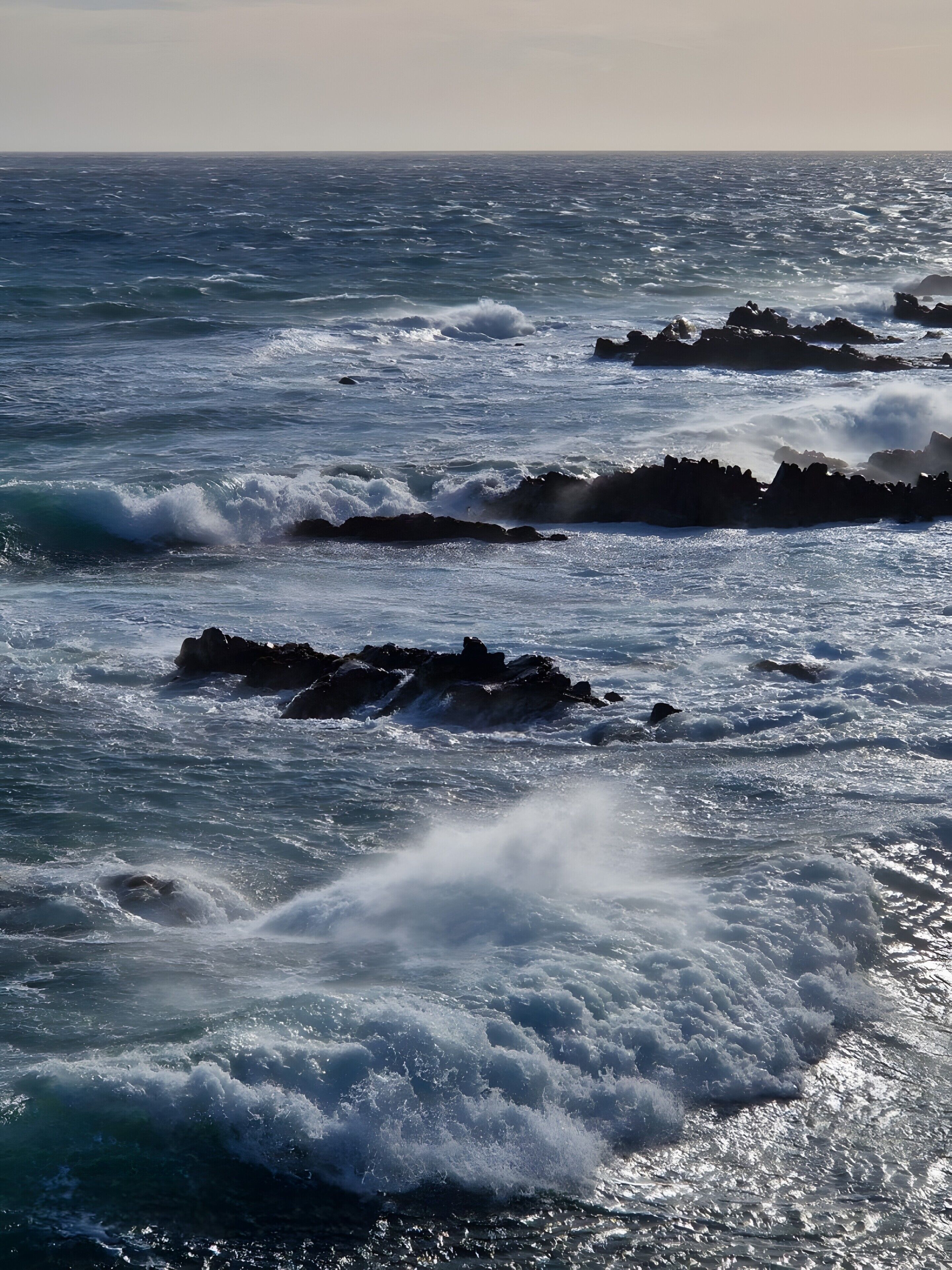 A coastal scene with waves crashing against rocky outcrops.