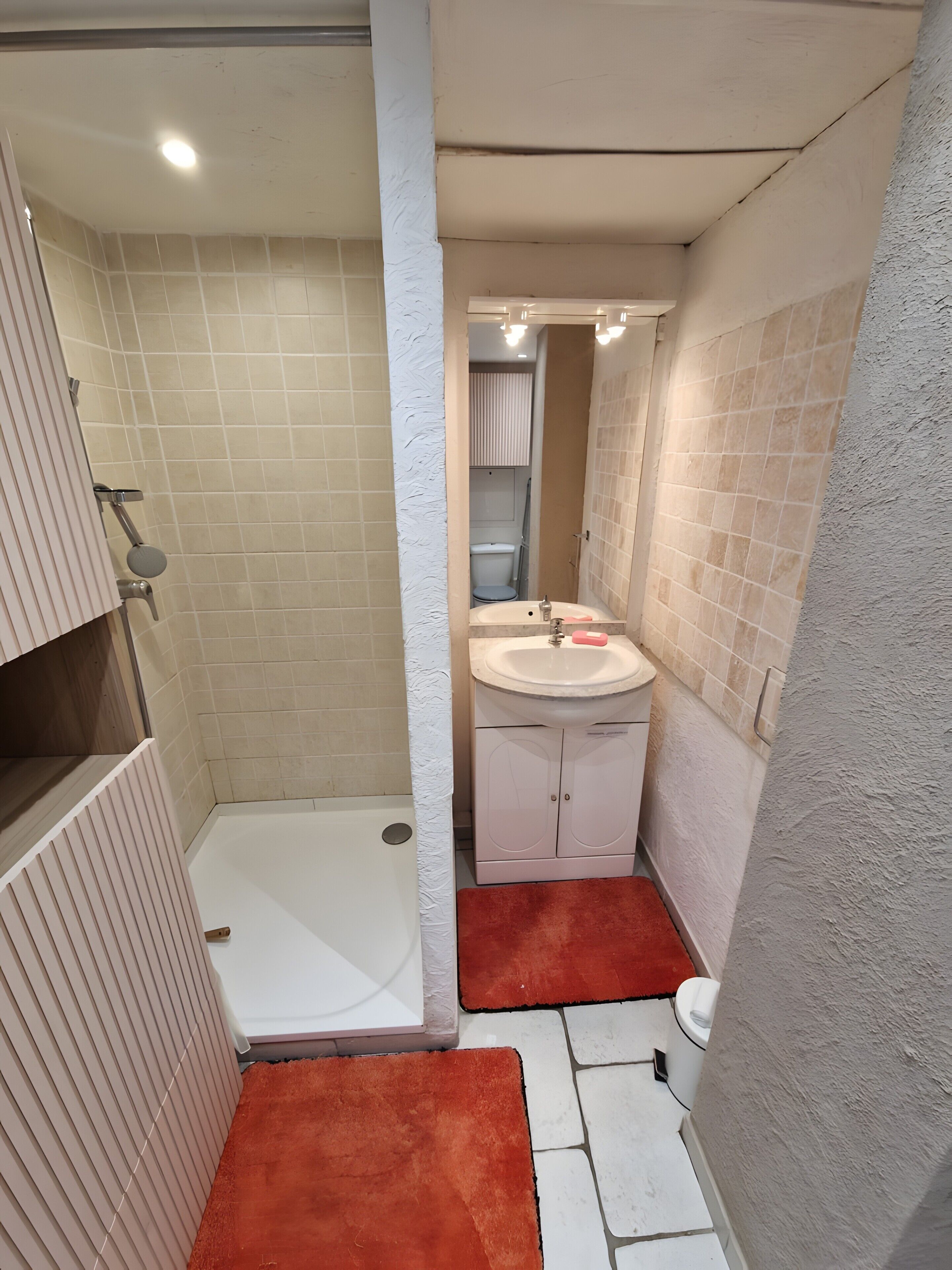 Ein Badezimmer mit Dusche, Toilette, Waschbecken und einem kleinen Schrank.