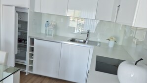 Une cuisine moderne avec des armoires blanches, un plan de travail en verre et un plancher en bois.