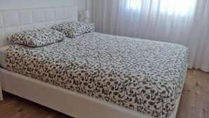 Une chambre à coucher avec un lit, une table de chevet et une fenêtre avec des rideaux.