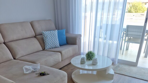 Un salon moderne avec un canapé beige, une table basse ronde et une vue à travers une porte vitrée.