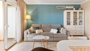Uma sala de estar com sofá, duas mesas laterais, um armário e uma luminária.