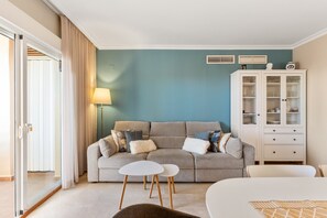 A living room with a sofa, two side tables, a cabinet, and a lamp.