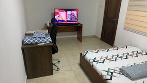 Ένα υπνοδωμάτιο με ένα κρεβάτι, ένα γραφείο με έναν υπολογιστή, μια καρέκλα και μια ντουλάπα.