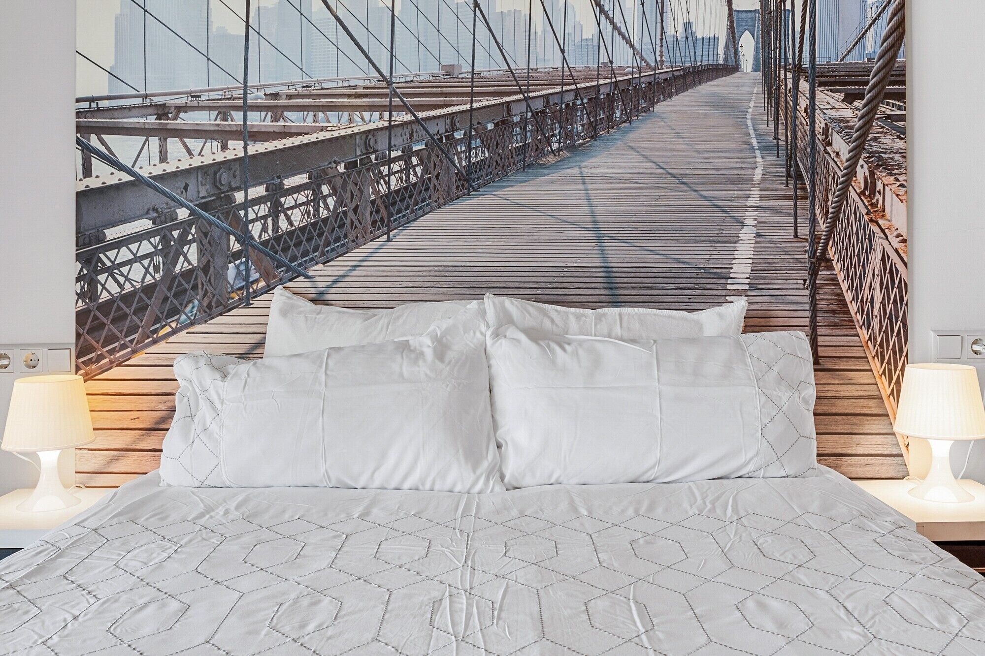 A bed with a geometric patterned bedspread, two white pillows, and two bedside lamps.