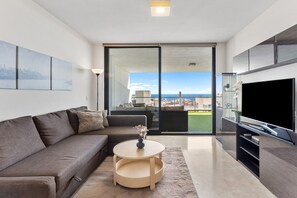 A modern living room with a sofa, a round coffee table, and a TV on a stand. - Apartment 'Gran Terraza con Vistas al Mar A111' with Wi-Fi and Air Conditioning (Mijas Costa)