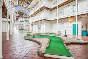 Ein geräumiger Atrium mit mehreren Ebenen, einer zentralen, künstlichen Rasenfläche und einer hohen Decke mit freiliegenden Balken.