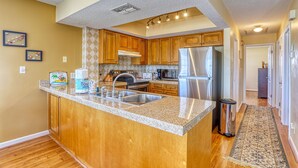 A kitchen with wooden cabinets, a granite countertop, stainless steel appliances, and a tiled backsplash.