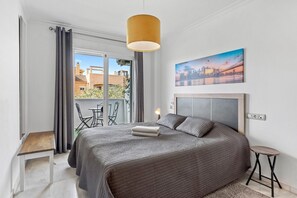 Une chambre à coucher avec un lit, une table de chevet, une chaise, une lampe et un tableau au mur.