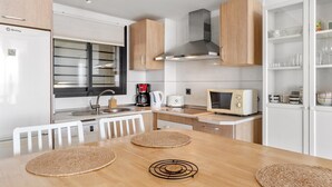 Una cocina compacta equipada con refrigerador, estufa, microondas y cafetera.