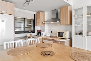 A compact kitchen with a refrigerator, stove, microwave, and a coffee maker.