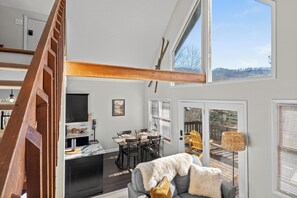A spacious living area with a high ceiling, a dining table, and a cozy seating area with a sofa.