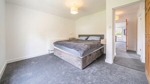 A bedroom with a large bed, a radiator, and a wooden door.
