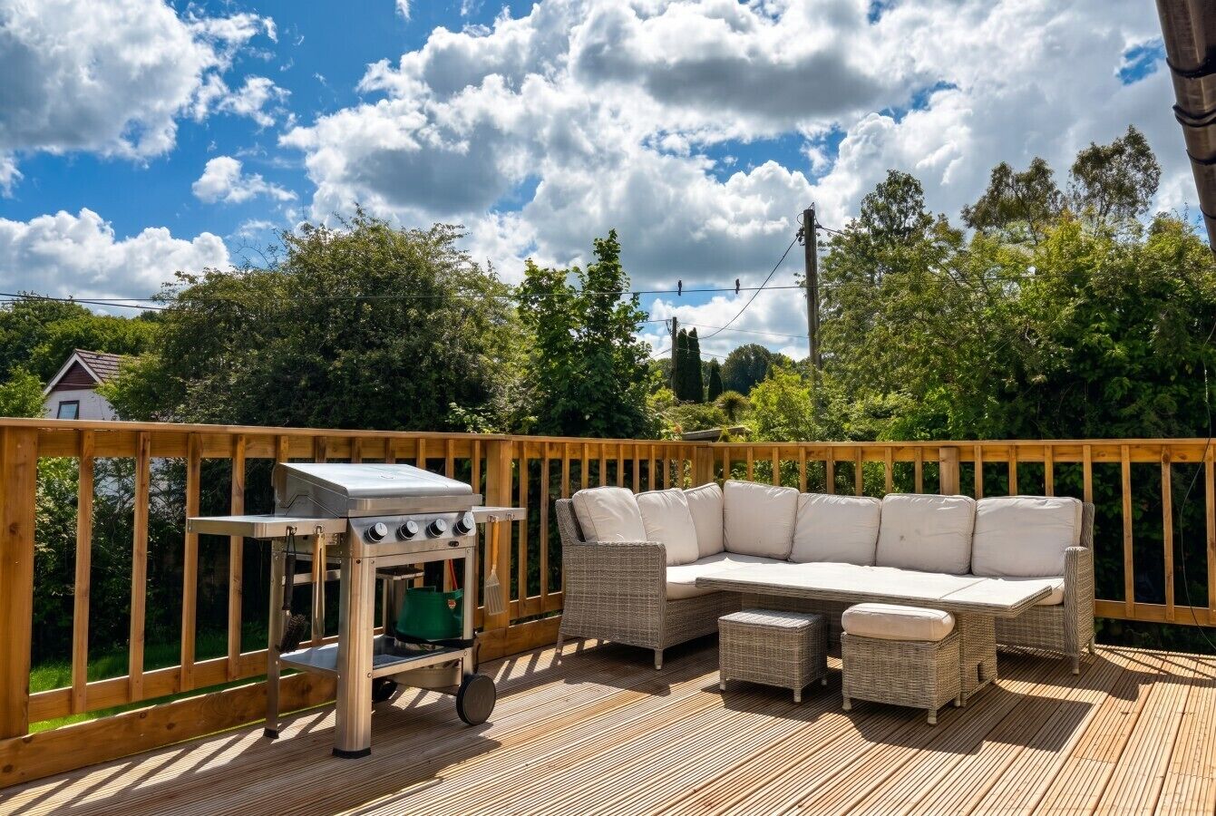Une terrasse dotée de mobilier d’extérieur, d’un barbecue et offrant une vue sur la verdure environnante.
