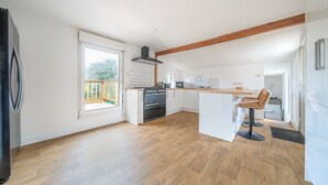 A modern kitchen with a central island, wooden flooring, and a view to a backyard.