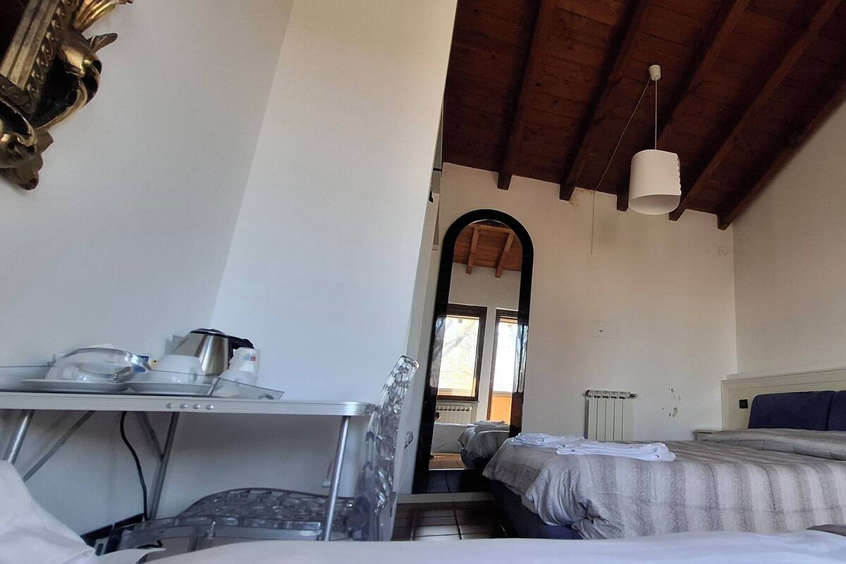 Une chambre avec un lit, un bureau avec une bouilloire, un miroir et une fenêtre.
