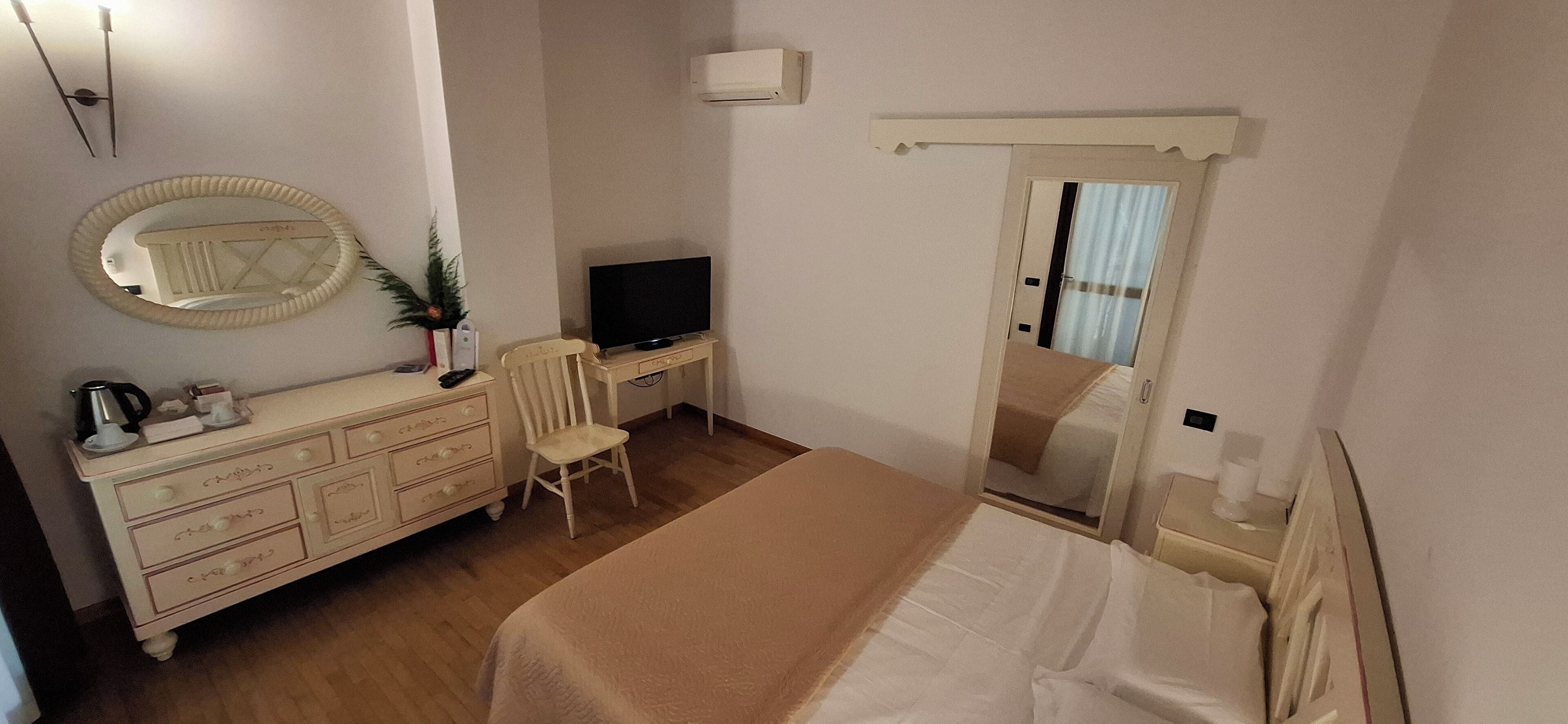 Un dormitorio con cama, cómoda, televisor y espejo.