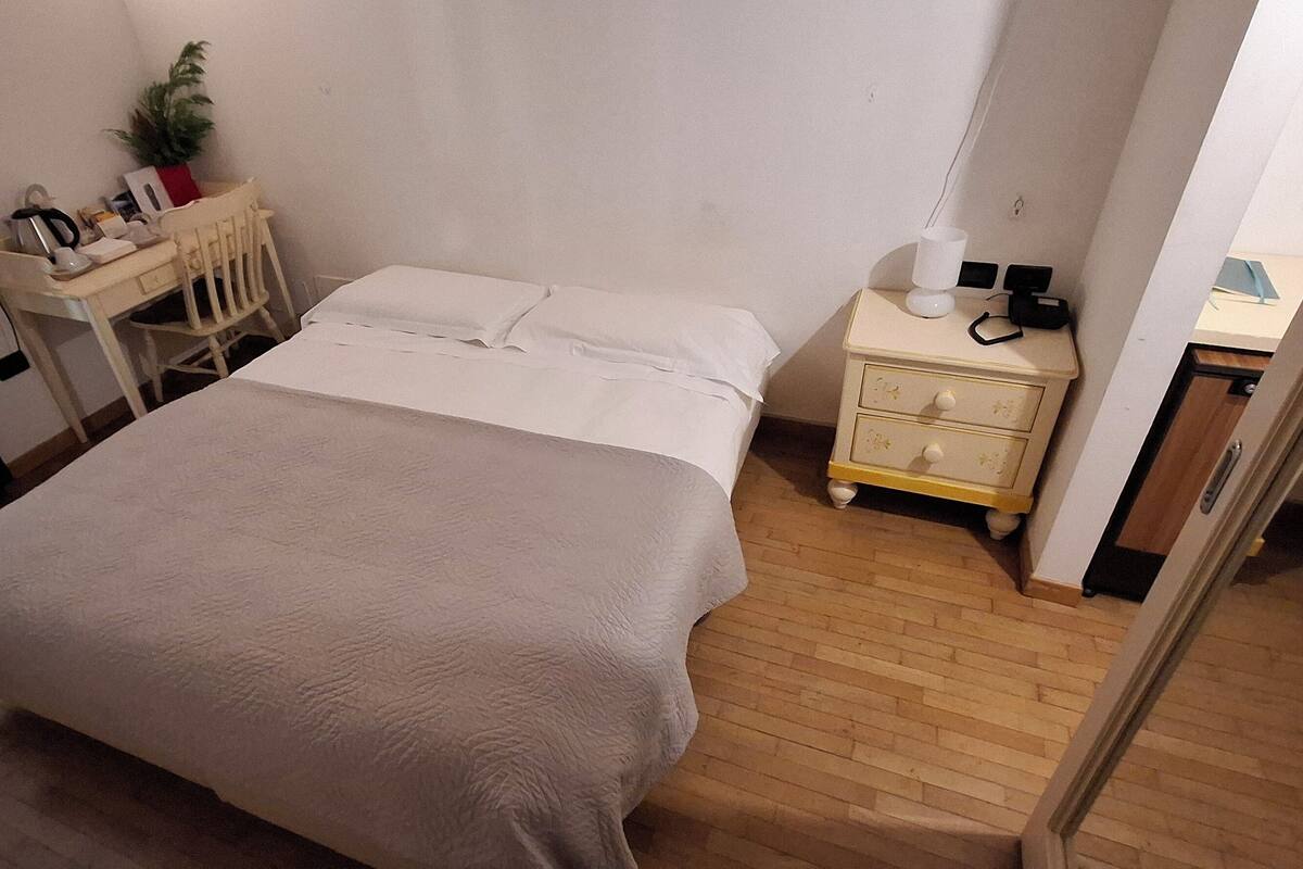 Une chambre à coucher comprenant un lit, une table de chevet et un bureau avec une chaise.