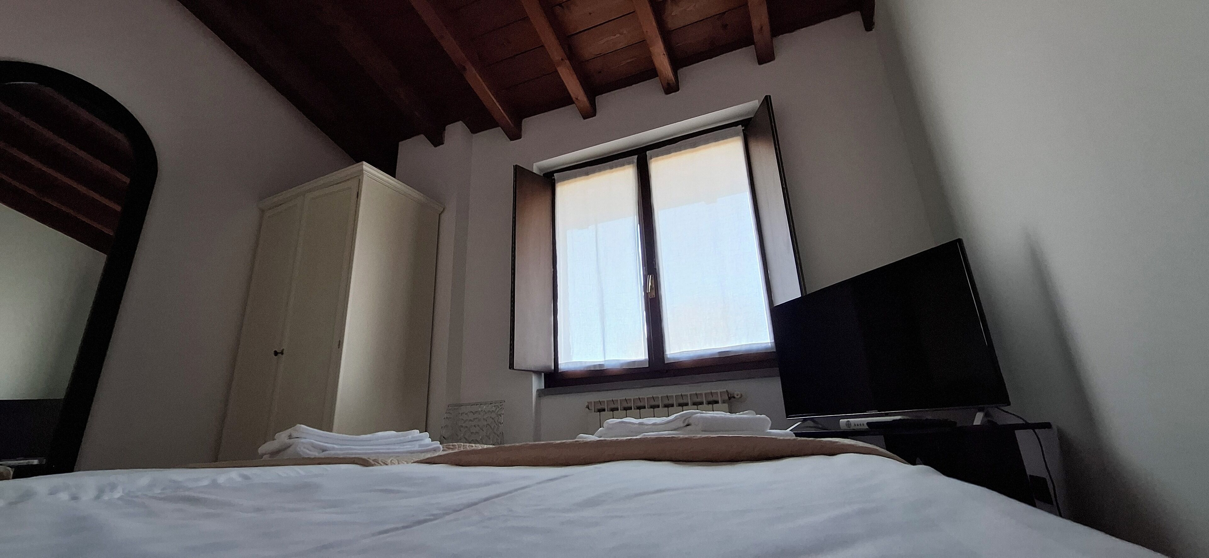 Une chambre à coucher avec un lit, une télévision, une fenêtre et une armoire.
