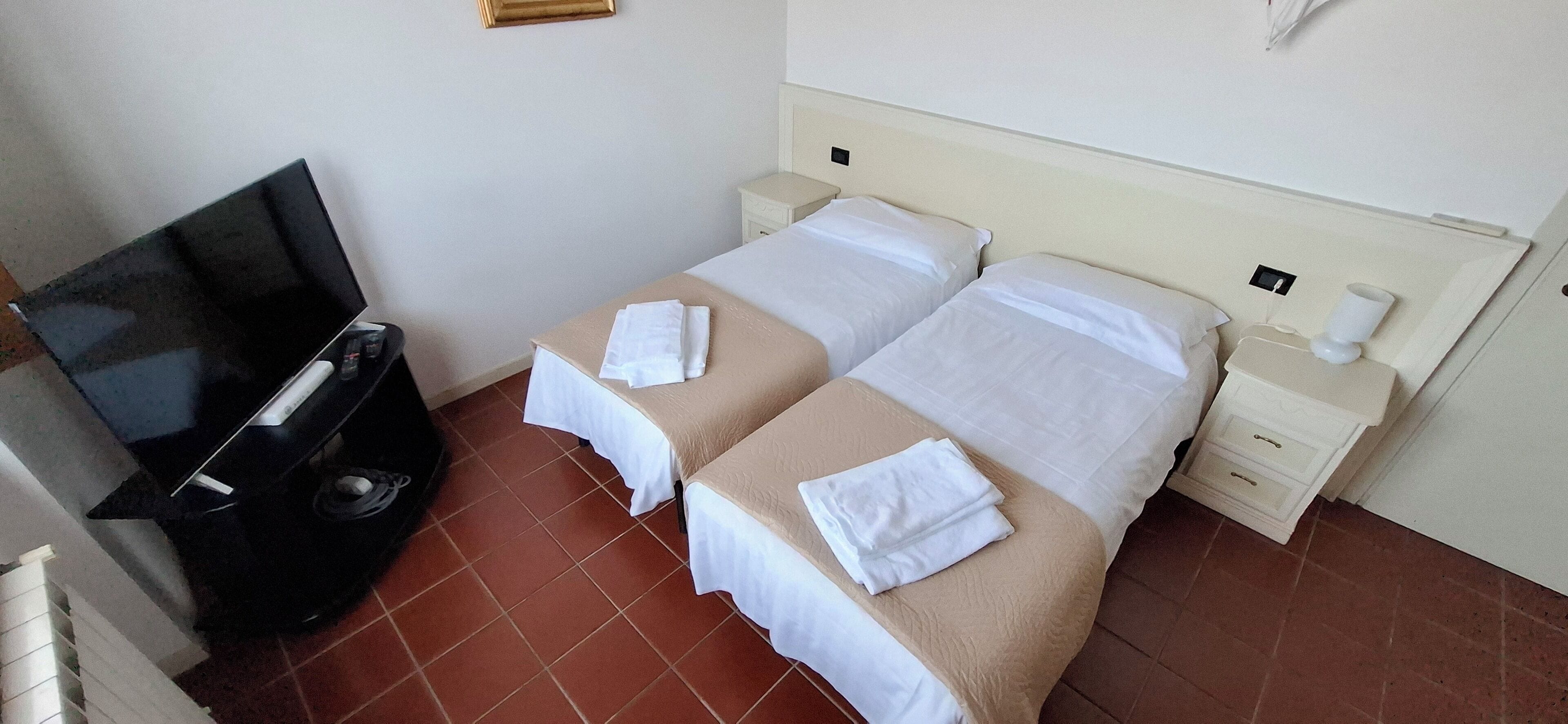 A hotel room with two beds, a TV, and a small table.