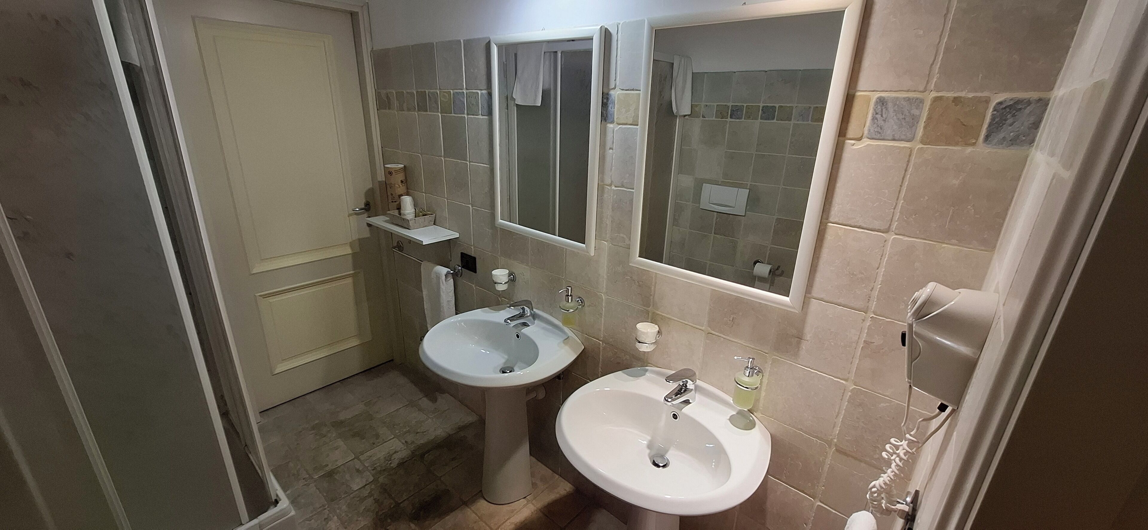 Un baño con dos lavamanos, ducha y espejo.