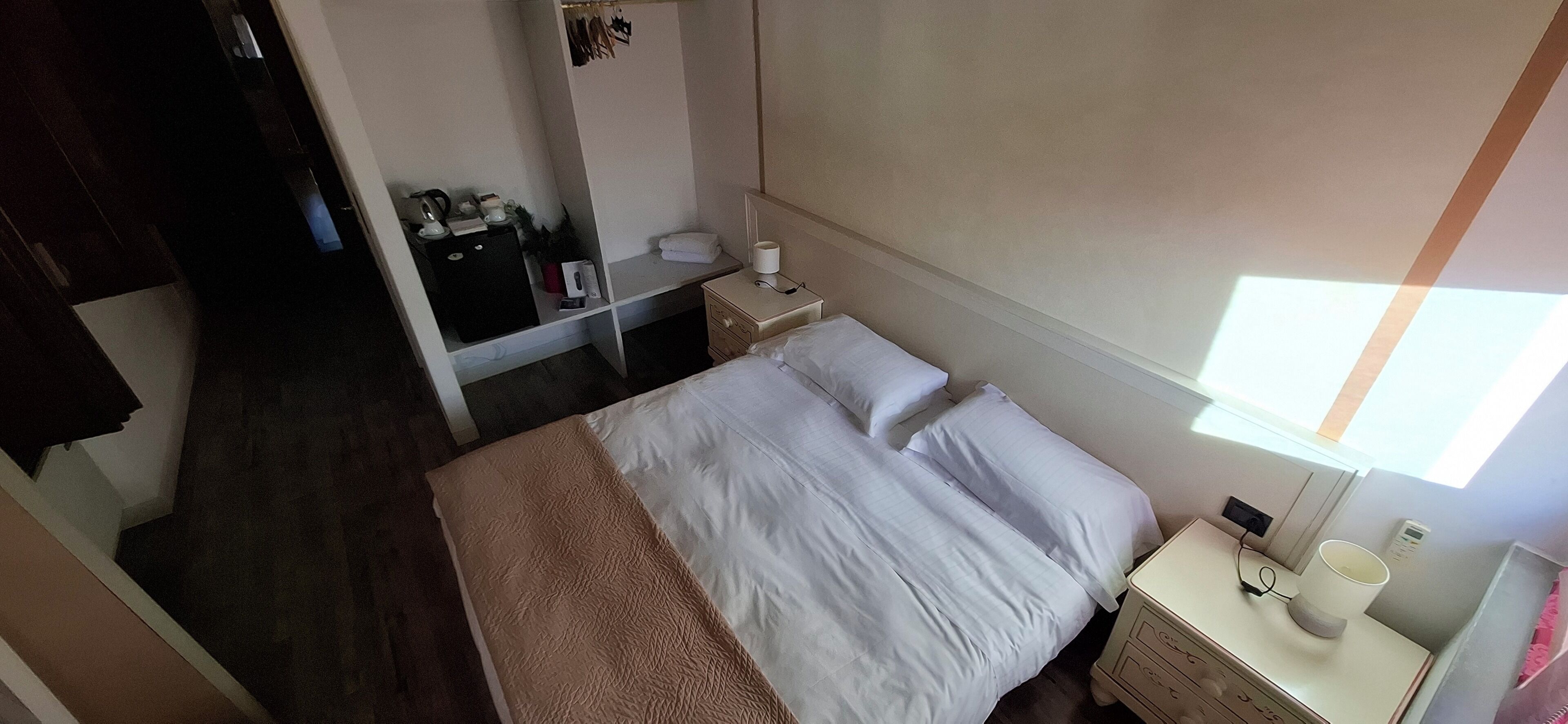 Une chambre d’hôtel comprenant un lit, une table de chevet, une lampe et un petit bureau avec une chaise.