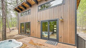 A modern cabin with a deck, large sliding glass doors, and a hot tub. - Secluded Modern Cabin- Near Flathead Lake (Polson)