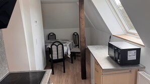 Una cocina compacta con estufa integrada, una mesa de comedor con sillas, un ventanal pequeño y un mueble de madera.
