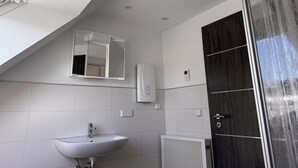Un baño moderno con un lavamanos blanco, un espejo, un radiador y una puerta de madera oscura.