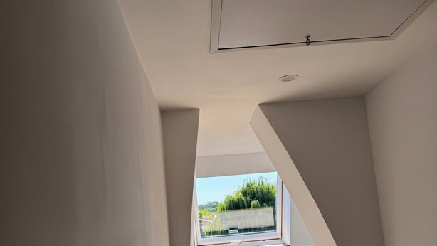Un interior moderno con techo inclinado, tragaluz y vistas al exterior con vegetación.