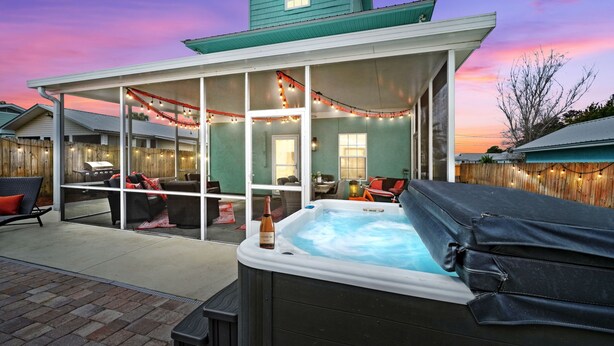 A covered patio area with a hot tub, outdoor seating, and string lights. - Spacious Beach Retreat, Pool, Hot Tub, Sleeps 14 (Panama City Beach)