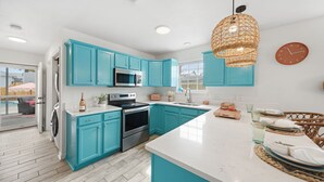 A modern kitchen with teal cabinets, stainless steel appliances, and a large island. - Spacious Beach Retreat, Pool, Hot Tub, Sleeps 14 (Panama City Beach)