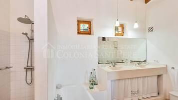 Un baño moderno con bañera, ducha, lavabo y tocador.