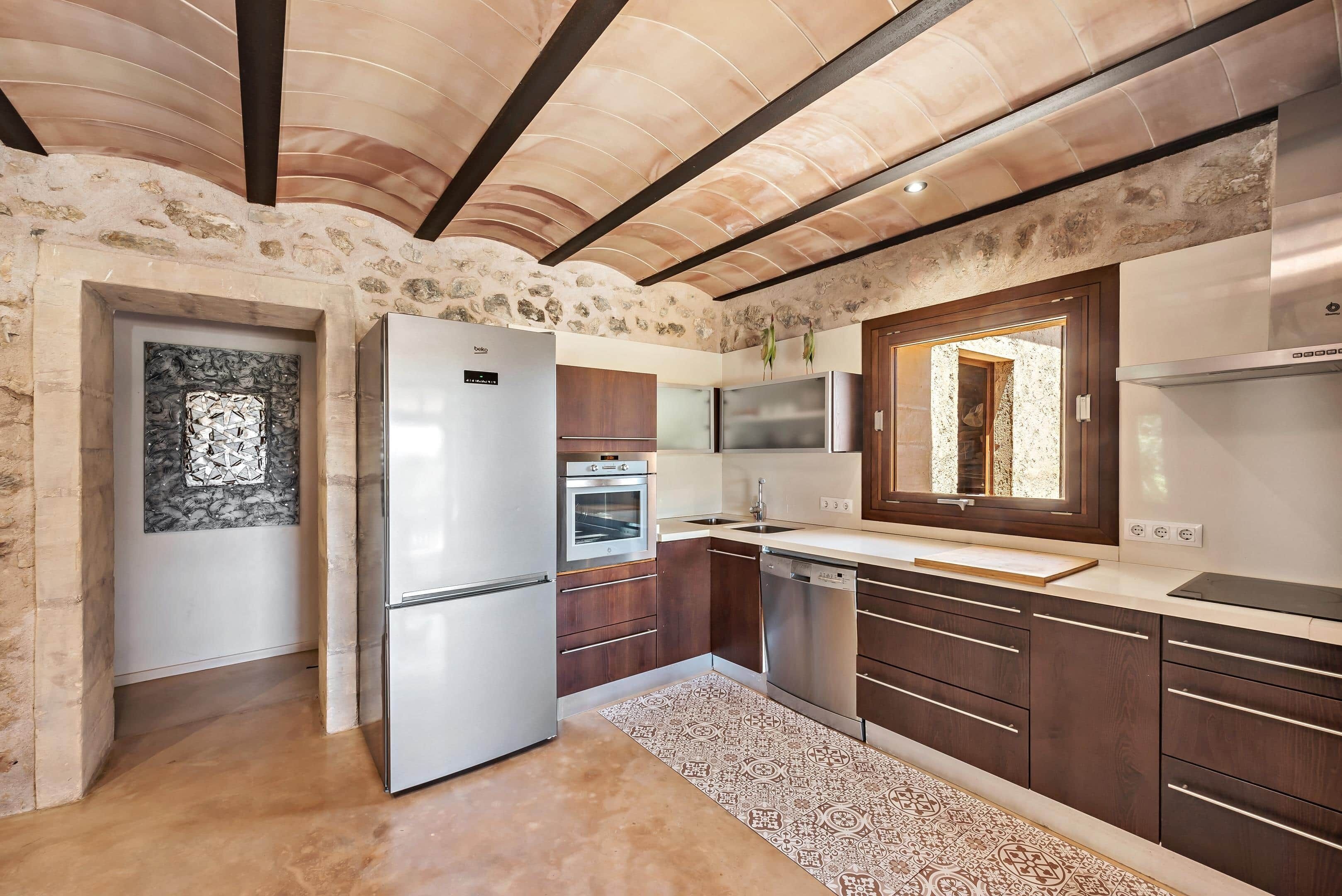 A kitchen with a stone wall, a refrigerator, an oven, a dishwasher, and wooden cabinets.