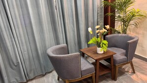 Eine Sitzecke mit zwei Polstersesseln, einem kleinen Holztisch und einem Blumentopf mit weißen Blüten.