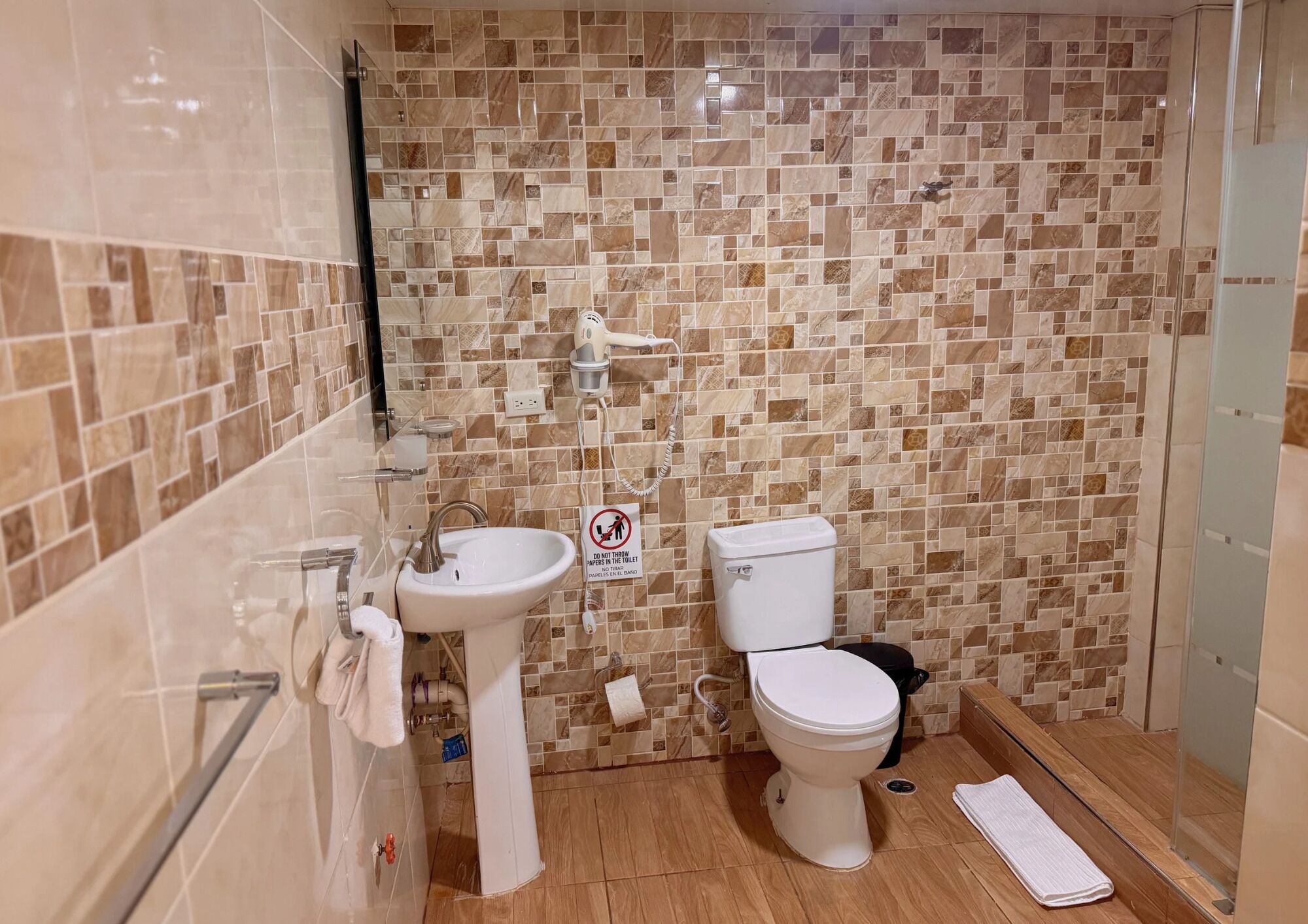 Une salle de bain avec un mur carrelé, un lavabo, des toilettes et un espace douche.