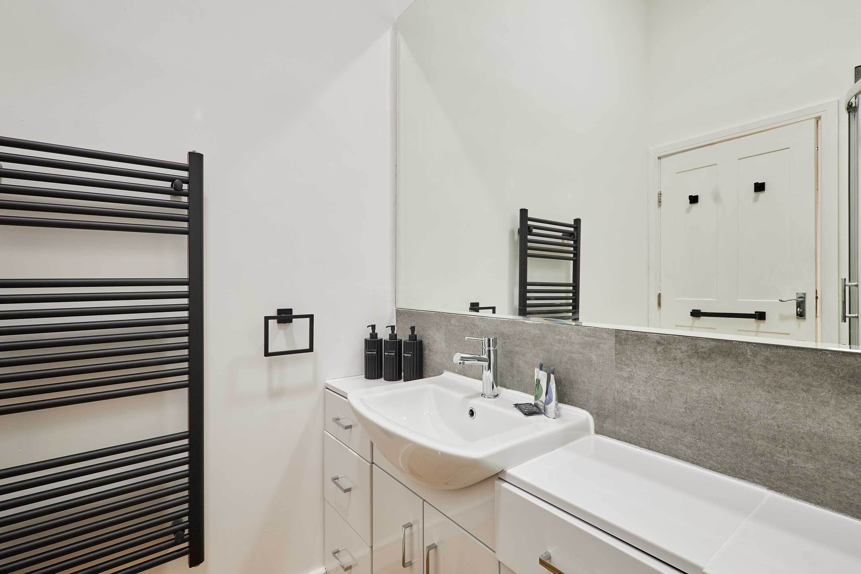 Un baño moderno con un lavamanos grande, un espejo y un perchero para toallas.