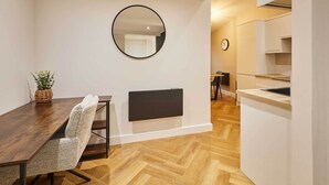 Una cucina moderna con piano cottura integrato, un'area pranzo con tavolo in legno e sedie decorate, e un grande specchio a parete.