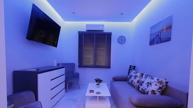 A modern living room with a flat-screen TV, a sofa, a coffee table, and a dining area. - Apartment 'Phidias House' with Balcony, Wi-Fi and Air Conditioning (Thessaloniki)