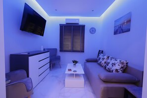 Ein modernes Wohnzimmer mit Flachbildfernseher, einer Couch, einem Couchtisch und einem Essbereich.