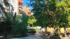 A city street with trees, a bench, and a building with balconies. - Apartment 'Phidias House' with Balcony, Wi-Fi and Air Conditioning (Thessaloniki)