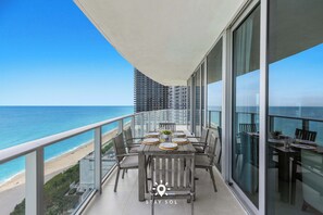 A balcony with a table set for dining, overlooking a beach and ocean. - Oceanline 3BR  Corner Balcony & Calm Seas (Hollywood)