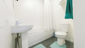Un baño con lavamanos, inodoro y bañera blancos.