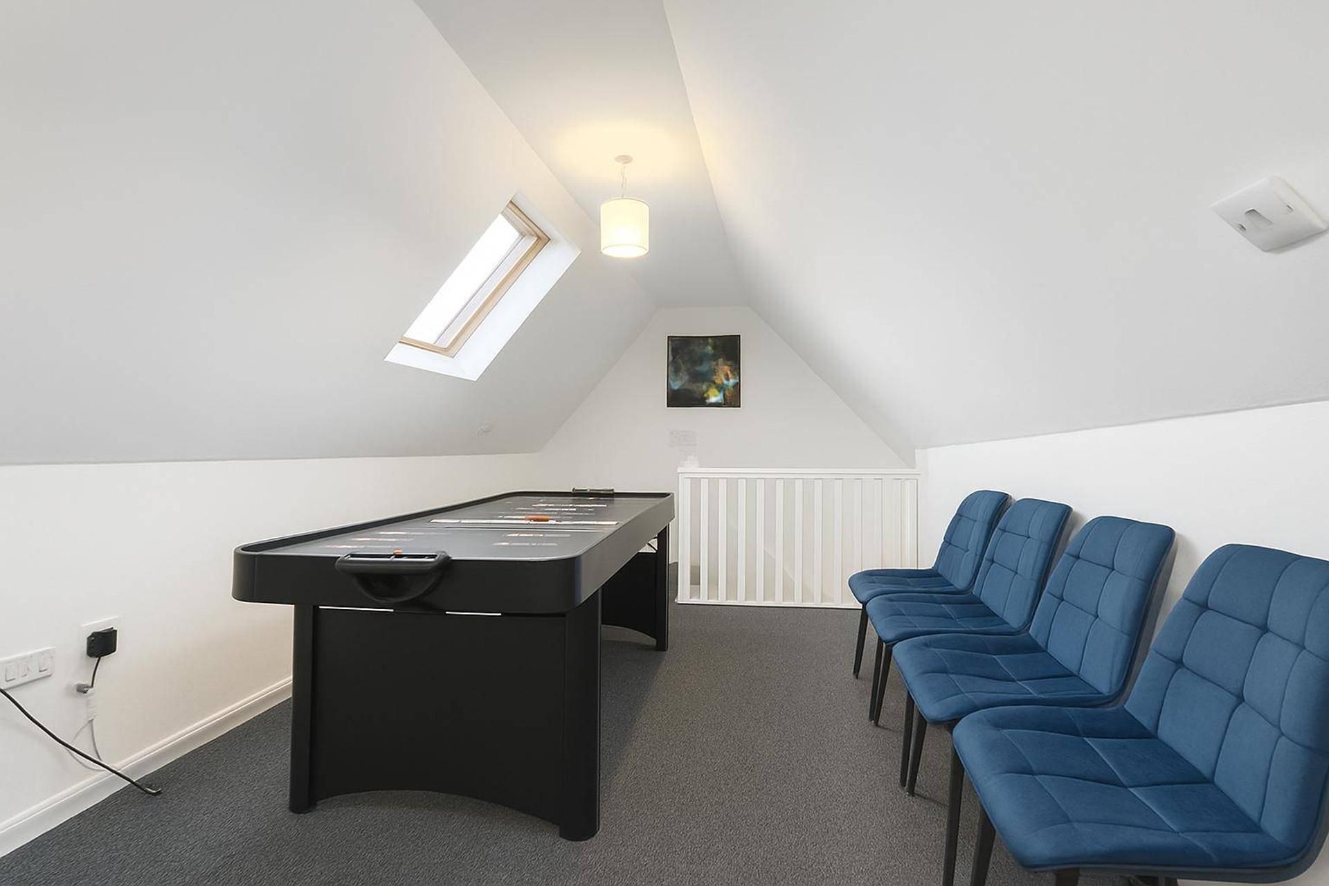 Ein Zimmer mit Billardtisch, Heizkörper und einer Reihe blauer Stühle.