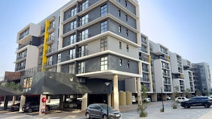 A multi-story residential building with balconies, a covered parking area, and a small commercial space with a sign. - The Millennial 425 (uMhlanga)