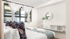 A hotel room with a bed, a bedside table, a mirror, and a window with curtains. - The Millennial 425 (uMhlanga)