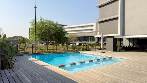 A modern building with a swimming pool, wooden deck, and outdoor seating area. - The Millennial 425 (uMhlanga)