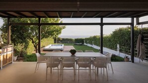 Une terrasse couverte avec une table et des chaises, un jacuzzi et une vue sur la mer.