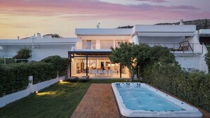 Une maison moderne dotée d’un patio couvert et d’un jacuzzi dans le jardin.