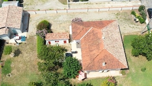 An aerial view of a residential area with two houses, one with a red-tiled roof and another with a grey roof. There are trees and a small garden area. - Gîtes Monplaisir - Maison Guyenne (Marmande)